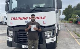 Swamy holding his CE 3a pass certificate in front of MT Training articulated lorry at the Manchester test centre